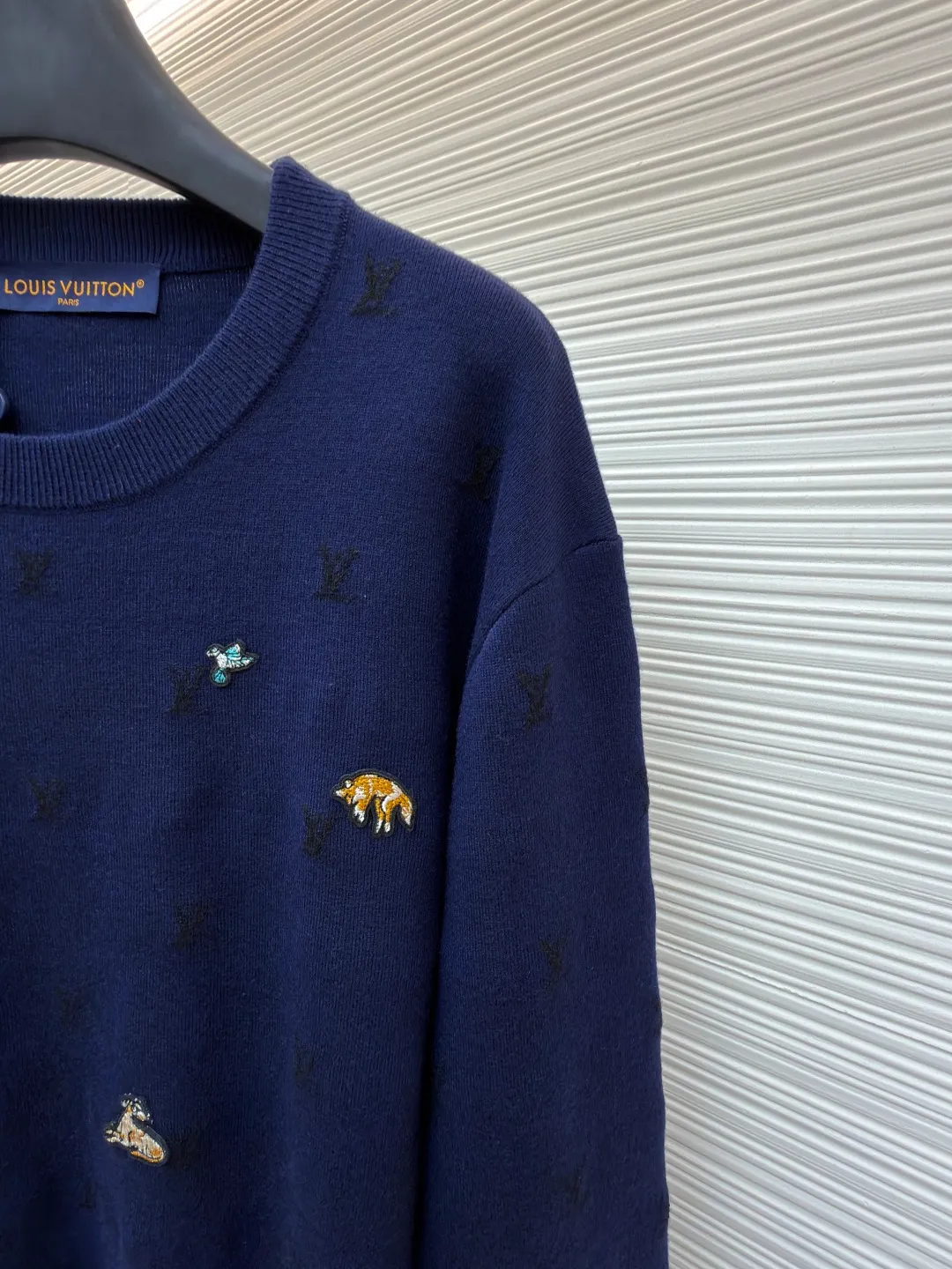 LOUIS VUITTON animal embroidered wool crew neck sweater ●Original version: purchased and developed by 18025 ●Item number: 1682089-B05 ●Fabric: wool blended fabric ●Technology: knitted embroidery production ●Color: navy blue ●Version: fitted version ●Weight: about 590 grams ●Size: XS-S-M-L ●Description: This Louis Vuitton navy blue sweater is made of ultra-fine merino wool blended yarn and is knitted by worsted knitting technology. It uses 16-needle high-density plain knitting technology to give the fabric a silky delicate touch and matte texture. The base of the body is also woven with a mini Monogram pattern using a same-color dark jacquard technology. The pattern is low-key and naturally blends with the wool texture. The decorative details embellished on the body are made of hand-made beading and metal veneer inlays. The veneer is aged by electroplating and enamel color-filled. Every decoration is hand-positioned and sewn by craftsmen to ensure firmness and a beautiful arrangement. The round neckline adopts double-needle overlock knitting technology, which is not easy to deform and fits the neck. The side seams and hem of the body use seamless splicing technology to reduce friction when wearing. The overall stitching is even and fine, fully demonstrating the brand's exquisite craftsmanship and detail control in the field of knitted garments. The overall wiring is straight and delicate, the fabric is comfortable and soft, and the color is consistent without color difference. It can be matched with the same style to create a fashionable look and control various occasions. Customized accessories, complete with three standards, same style for men and women!